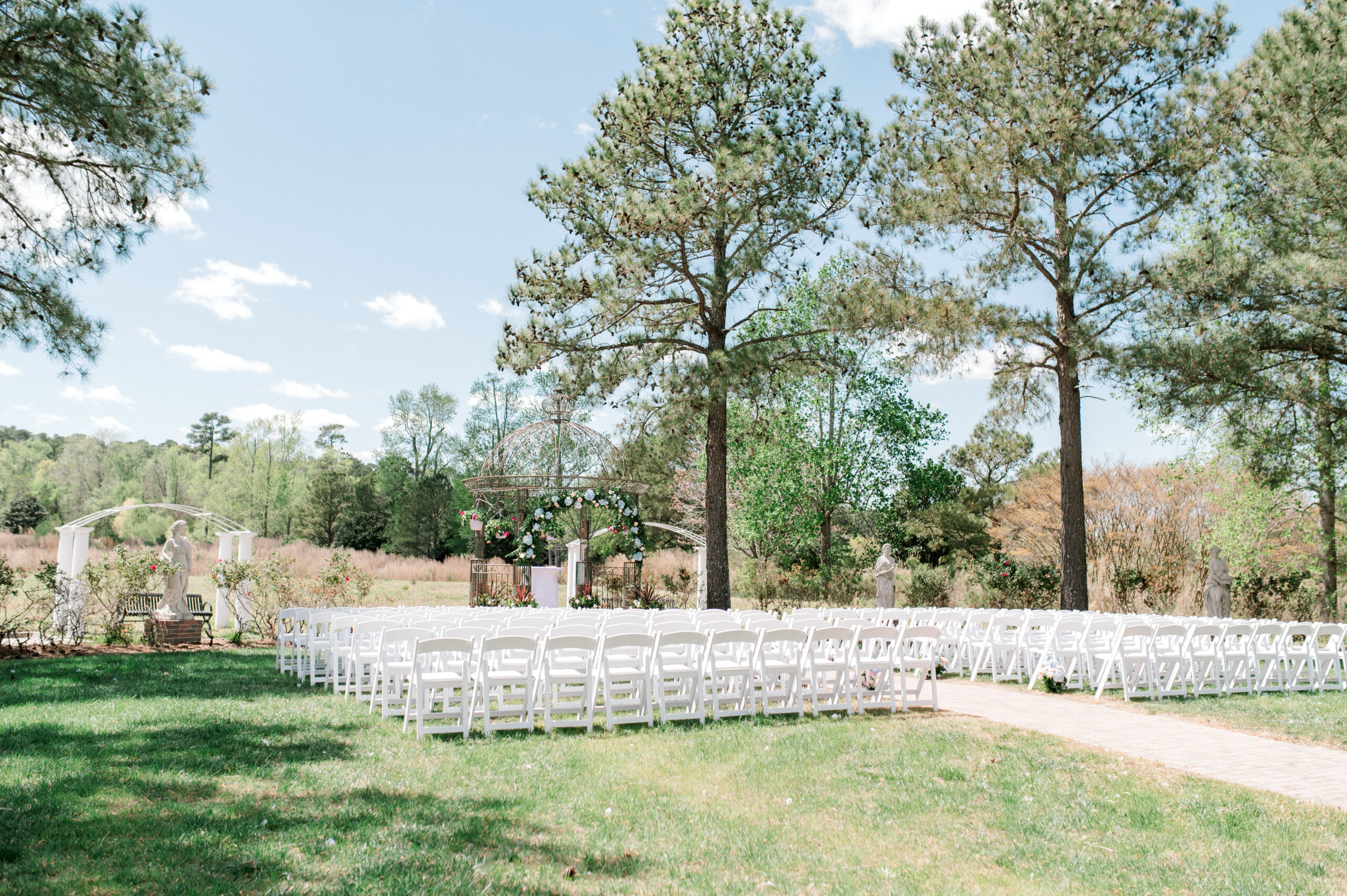 Large trees surround chairs and wedding arch at a beautiful Northern Virginia wedding venues